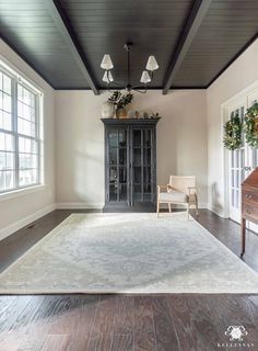 a living room with white walls and wood flooring on the wooden floors is furnished with an antique china cabinet