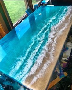 the table is made out of glass and has an ocean wave painted on it's surface