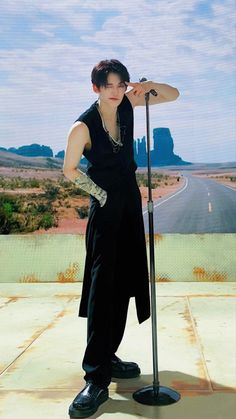 a man standing on the side of a road next to a pole