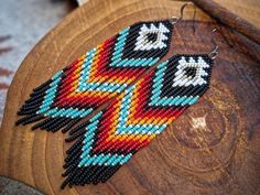 the beaded earrings are made with different colors and designs on wood sliced surface