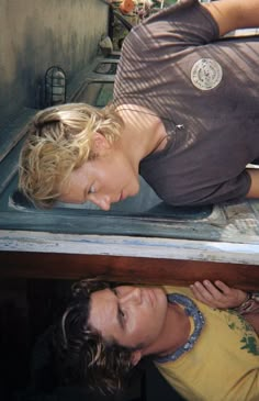 a man and woman laying on the back of a truck with their eyes closed, looking at each other