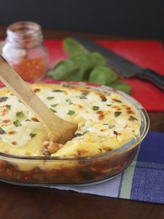 a casserole dish on a table with a wooden spoon