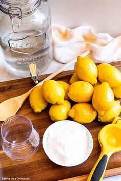 some lemons are sitting on a cutting board next to a glass jar and spoon