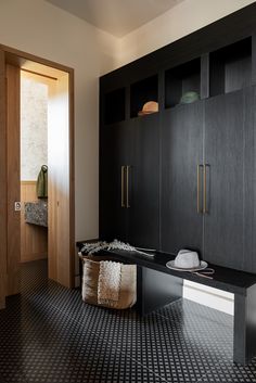 a black and white tiled floor in a room with wooden cabinets, a hat on top of the bench