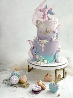 a three tiered cake decorated with pastel colors and seashells on a stand