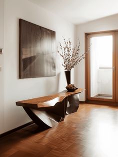 a vase filled with flowers sitting on top of a wooden table next to a doorway