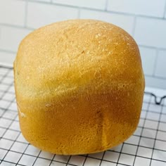 a loaf of bread sitting on top of a cooling rack next to a white tiled wall