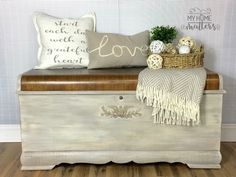 a white chest sitting on top of a wooden floor next to a pillow and blanket