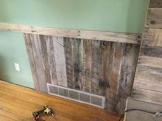 a wall made out of pallet wood with a heater on the floor next to it