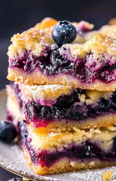 blueberry bars stacked on top of each other with powdered sugar and fresh berries