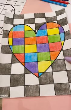 a piece of paper with a heart drawn on it and colored pencils next to it