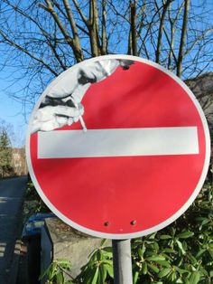 a close up of a red and white street sign with trees in the back ground