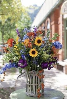 a basket filled with lots of colorful flowers on top of a table next to a building