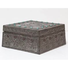 an ornate metal box with turquoise beads on the top and bottom, sitting on a white surface