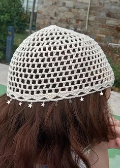 a woman wearing a white crocheted hat with stars on the brim and hair