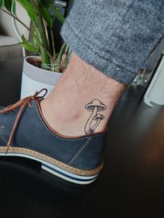 a person's foot with a mushroom tattoo on the left side of their shoe