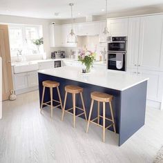 a kitchen with two stools next to an island in the middle of the room