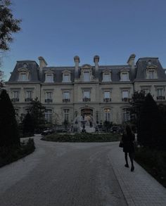 a woman is walking towards a large building