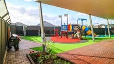 An outdoor childcare playground with a platfrom connected to the grass floor with climbing rope and attached to a blue and yellow slide. Climbing Rope