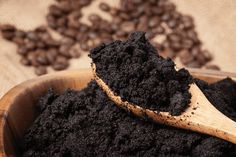 a wooden spoon filled with dirt next to coffee beans