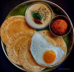 a plate with pancakes, eggs and sauces on it