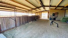 the inside of a horse barn with hay in it and a fenced in area