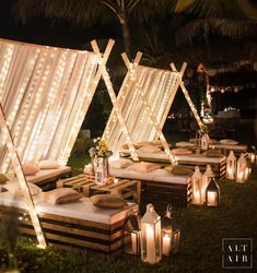 an outdoor seating area with candles and lights on the grass, surrounded by palm trees