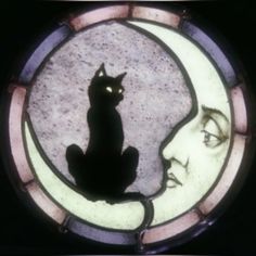 a stained glass window with a cat sitting on the moon