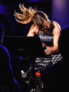 a woman with long hair sitting on top of a piano in front of a crowd