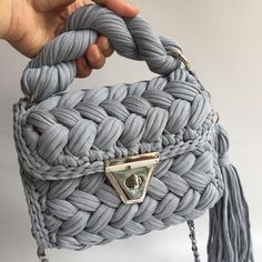 a handbag is being held up by someone's hand with a tasseled handle