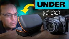 a camera sitting on top of a wooden table next to a bag with the words under $ 100