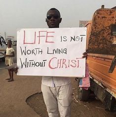 a man holding a sign that says life is not worth living without christ