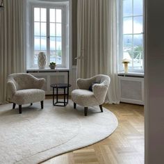 a living room with two chairs and a rug