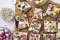 several pieces of cake sitting on top of a table next to bowls of candy and candies