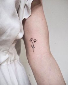 a small flower tattoo on the left arm