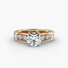 a yellow gold engagement ring with channel set diamonds on the sides and a round brilliant cut diamond in the center