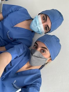 two women in scrubs and masks are looking up at the camera while standing next to each other