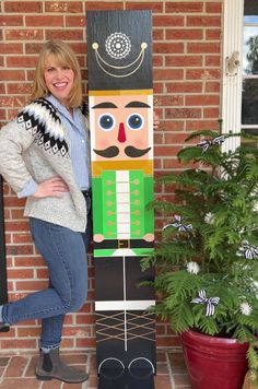 a woman standing next to a wooden nutcracker on the side of a brick building