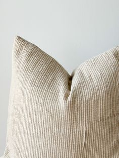 a close up of a pillow on a bed with white walls in the back ground