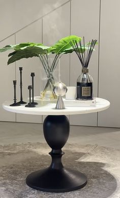 a white table topped with vases filled with plants and candles on top of a marble floor