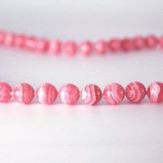 a pink beaded necklace on a white surface