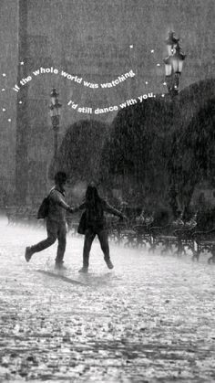 two people walking in the rain holding hands