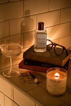 a candle and some books on a counter with a wine glass next to the glasses