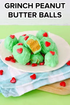 green peanut butter balls on a white plate with red heart shaped candies in the middle