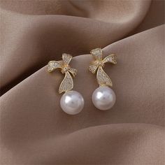 Take on the town in chic style when you jazz up your ensemble with these drop earrings fashioned with a sweet bow motif and pavé-set cubic zirconia details. 0.43" W x 1.06" L 18k gold-plated copper / pearl / cubic zirconia Formal Pearl Drop Earrings With Bow, Formal Pearl Earrings With Bow Detail, Elegant Drop Earrings With Decorative Bow Jewelry, Elegant Bow Pearl Earrings, Luxury Gold-tone Pearl Drop Earrings, Copper Pearl, Fashion Earrings, Chic Style, Cubic Zirconia