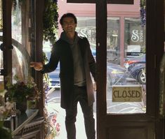 a man is standing in the doorway of a closed store with his hand on the door handle