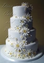 a white wedding cake with daisies on it