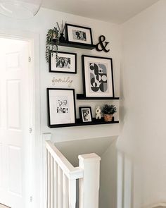 some black and white pictures hanging on the wall next to a stair case in a home