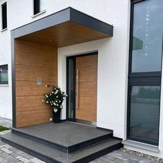 the front entrance to a modern home with flowers in a vase on the step next to it