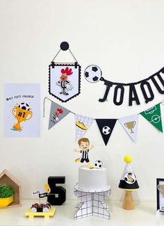 there is a birthday cake and decorations on the table in front of the white wall